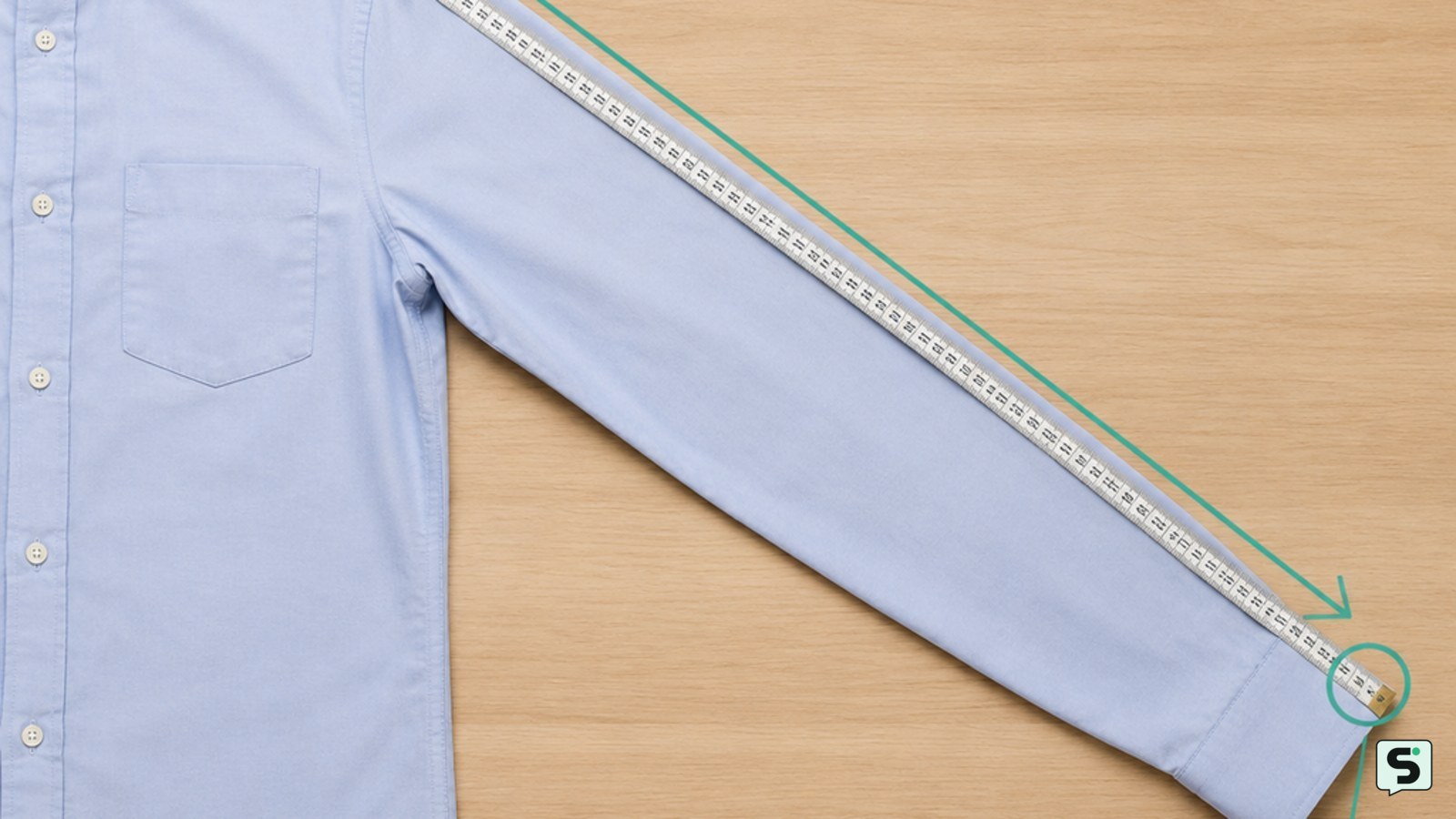 Camisa extendida sobre una mesa con la cinta métrica colocada desde la costura del hombro hasta el puño
